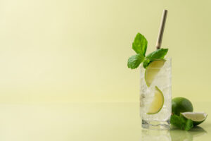 Verre de cocktail vodka citron frais servi avec des glaçons, des tranches de citron vert et de la menthe fraîche.