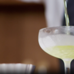 Un cocktail vodka citron est délicatement versé dans une coupe givrée pour une présentation élégante et rafraîchissante.