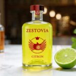 Bouteille de liqueur de citron Zestovia à côté d'un citron vert pour la préparation du cocktail vodka citron.