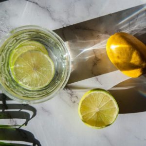 Des rondelles de citron vert infusent dans un verre avant l'ajout de la vodka citron et de l'eau pétillante pour créer un cocktail frais et désaltérant.